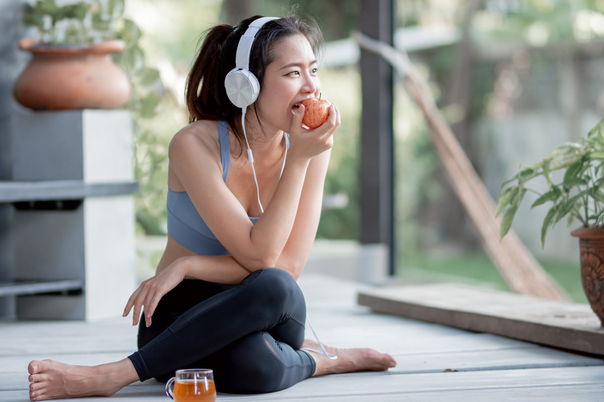 A healthy and sporty woman enjoying an apple in her condo in Laguna, promoting a balanced lifestyle in a serene environment.